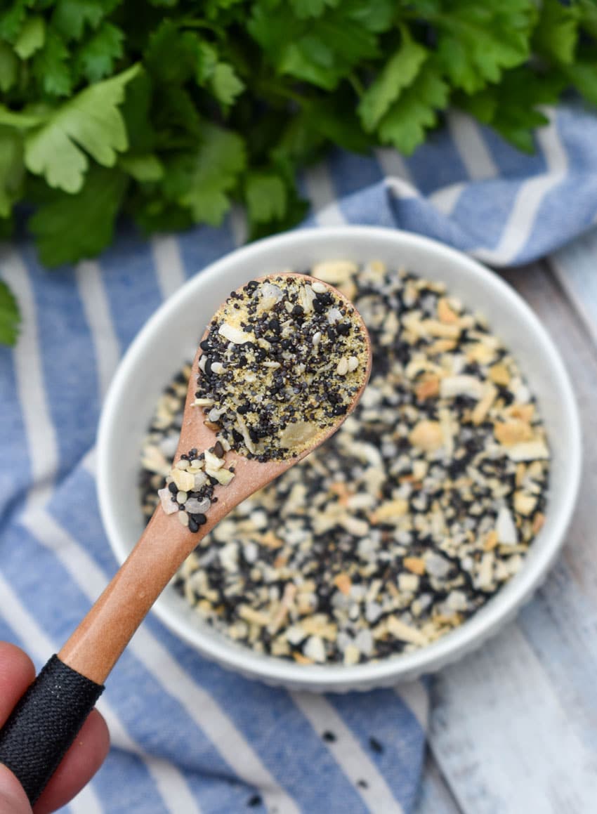 a small wooden spoon holding up a scoop of homemade everything bagel seasoning