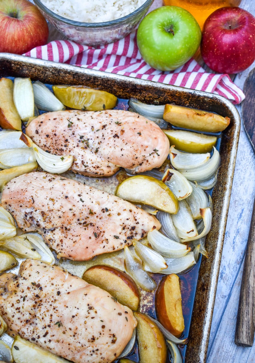 roasted chicken with apples and onion on a metal sheet pan