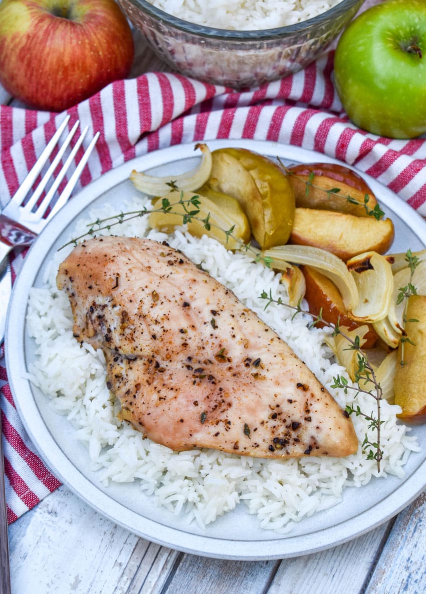sheet pan chicken and apples over steamed white rice on a white plate