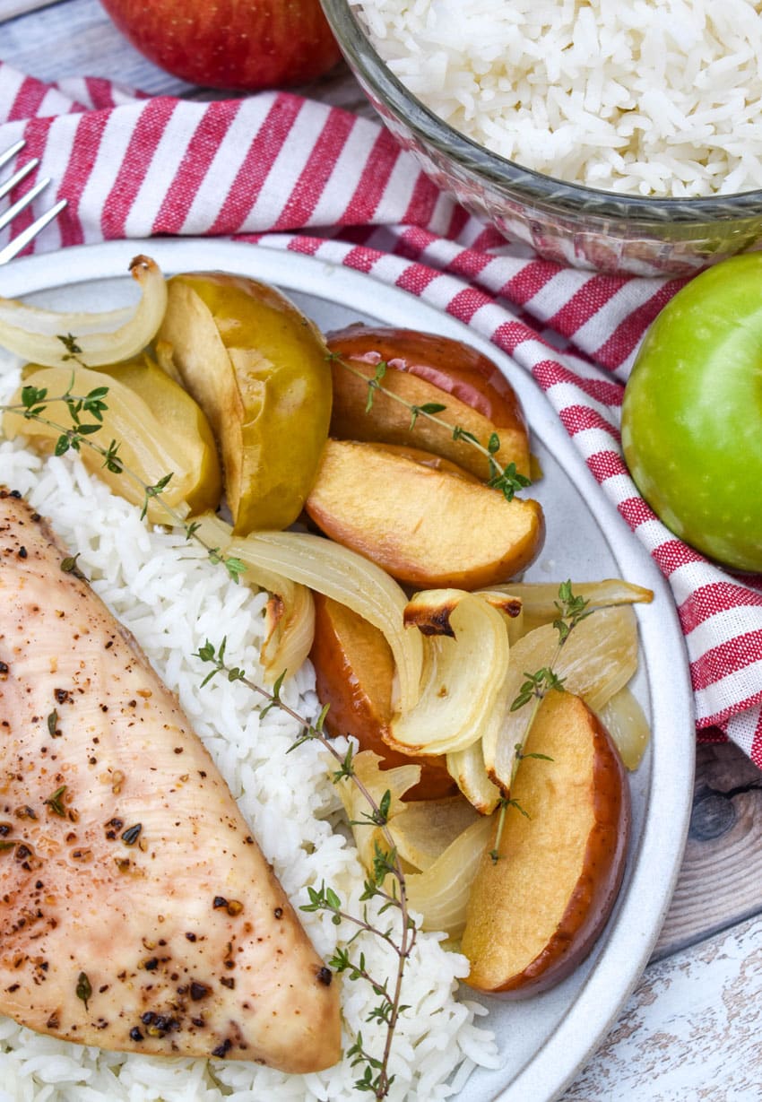 sheet pan chicken and apples over steamed white rice on a white plate
