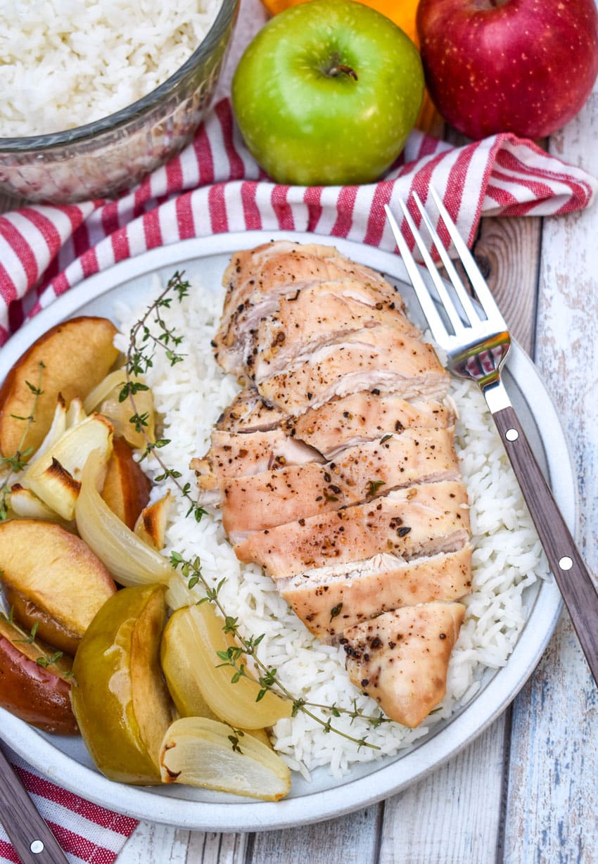 sheet pan chicken and apples over steamed white rice on a white plate