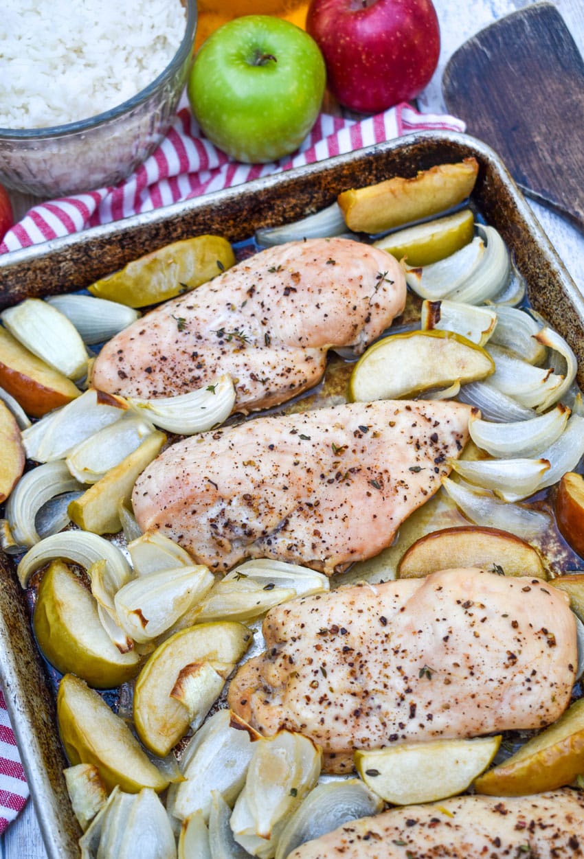 roasted chicken breasts with apples and onion on a metal sheet pan