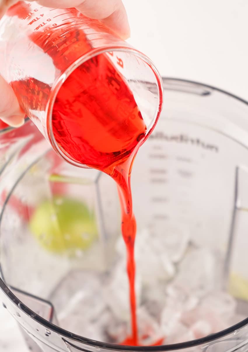 grenadine being poured over ice in a blender