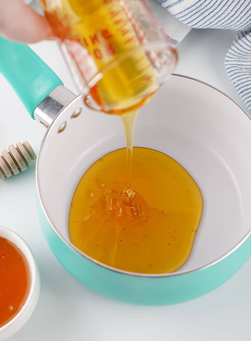 honey being poured into a small kitchen pot