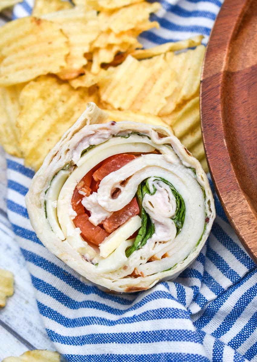 a copycat costco turkey swiss pinwheel on a cloth napkin with potato chips in the background