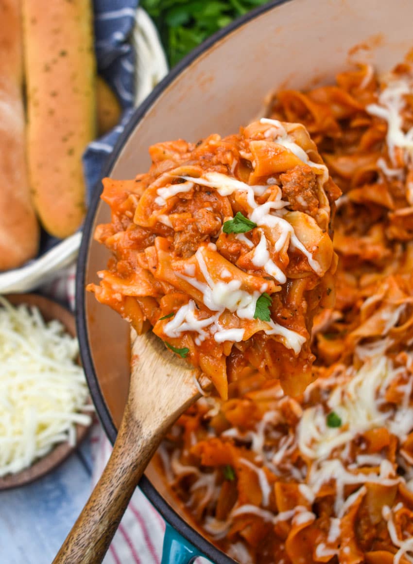 a wooden spoon holding up a scoop of homemade hamburger helper lasagna