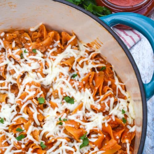 homemade hamburger helper lasagna topped with melted shredded mozzarella cheese in a large Dutch oven
