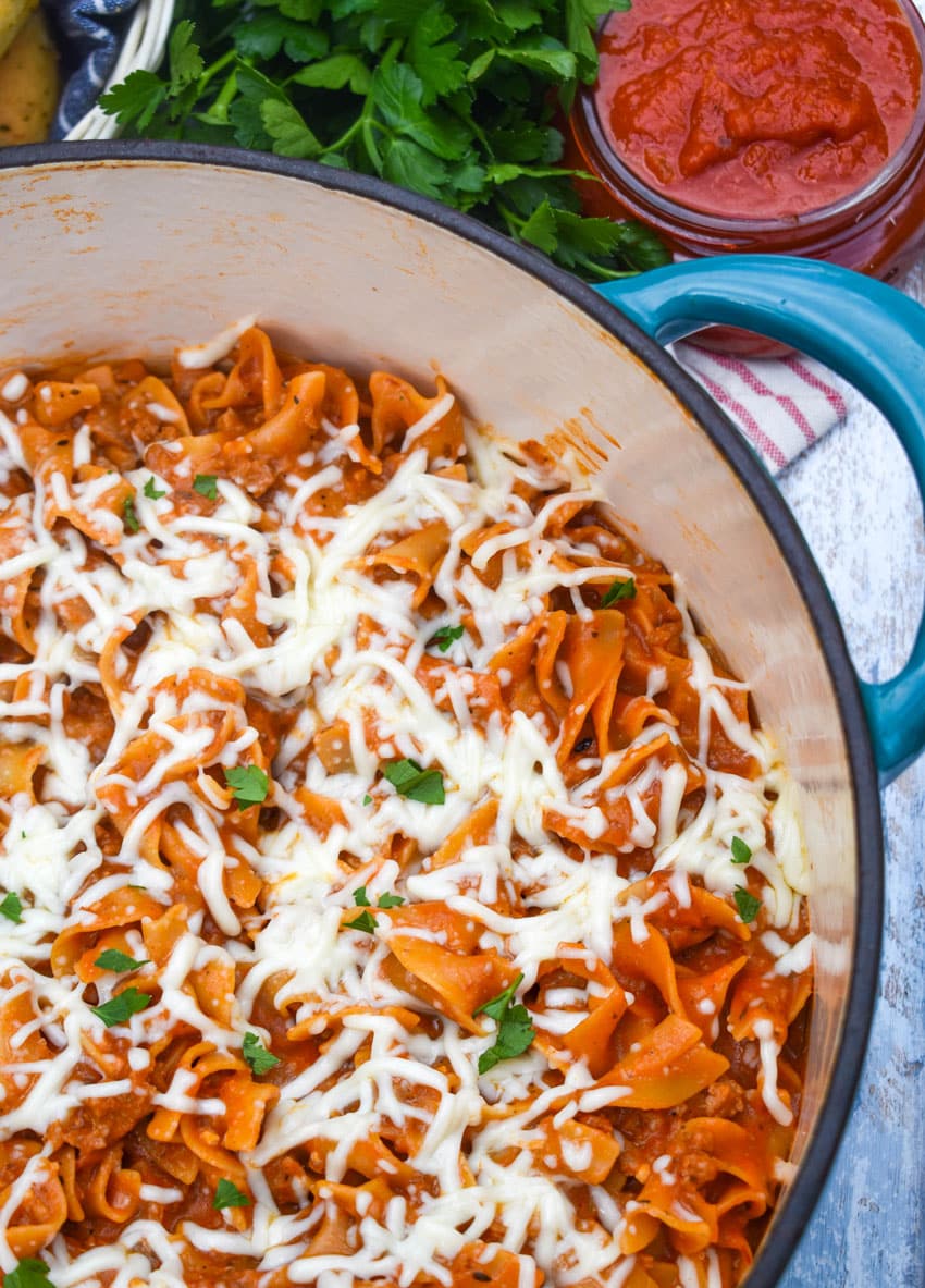 homemade hamburger helper lasagna topped with melted shredded mozzarella cheese in a large Dutch oven