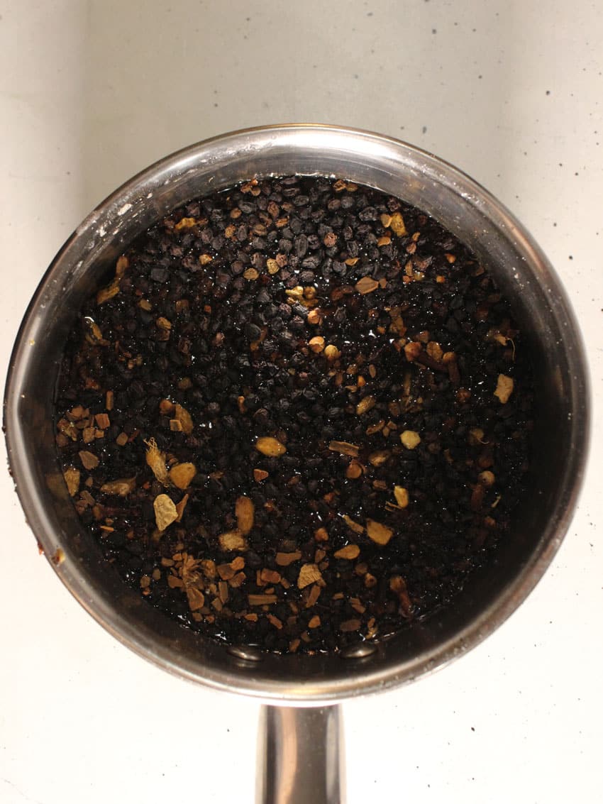 dried elderberries and herbs in a small metal pot