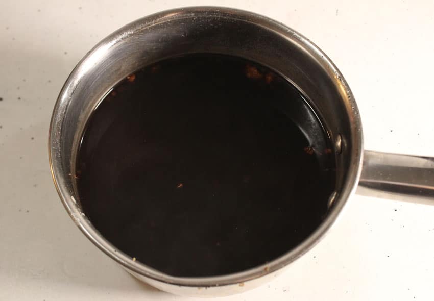 strained homemade elderberry syrup in a small metal pot