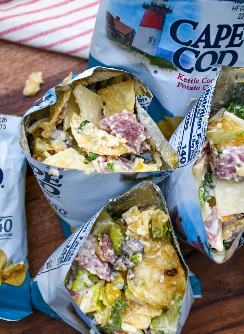 a group of prepared chip bag sandwiches on a wooden serving board