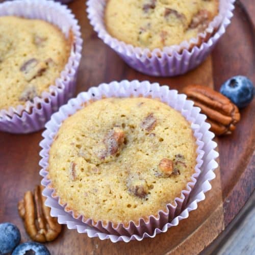 pecan pie muffins in purple paper liners on a wooden cake stand