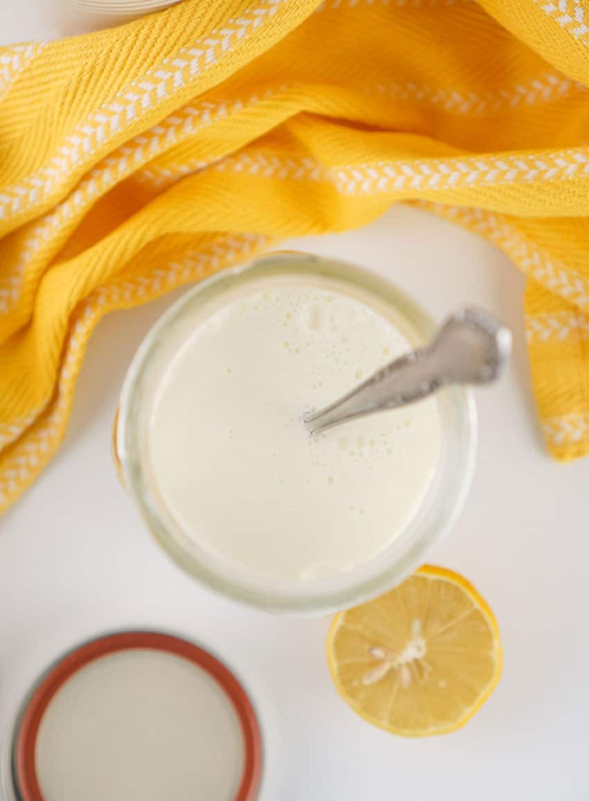 homemade buttermilk in a small glass jar resting on a wooden trivet