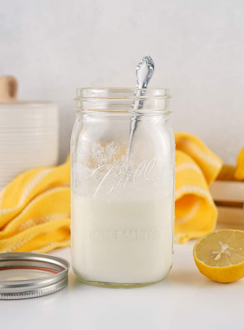homemade buttermilk in a small glass jar resting on a wooden trivet