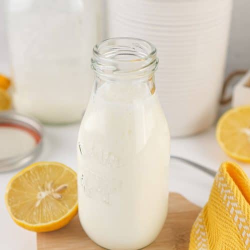 homemade buttermilk in a small glass jar resting on a wooden trivet