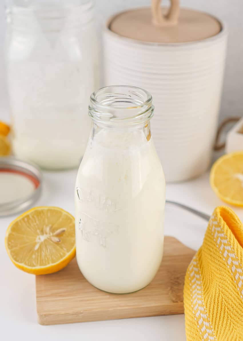 homemade buttermilk in a small glass jar resting on a wooden trivet