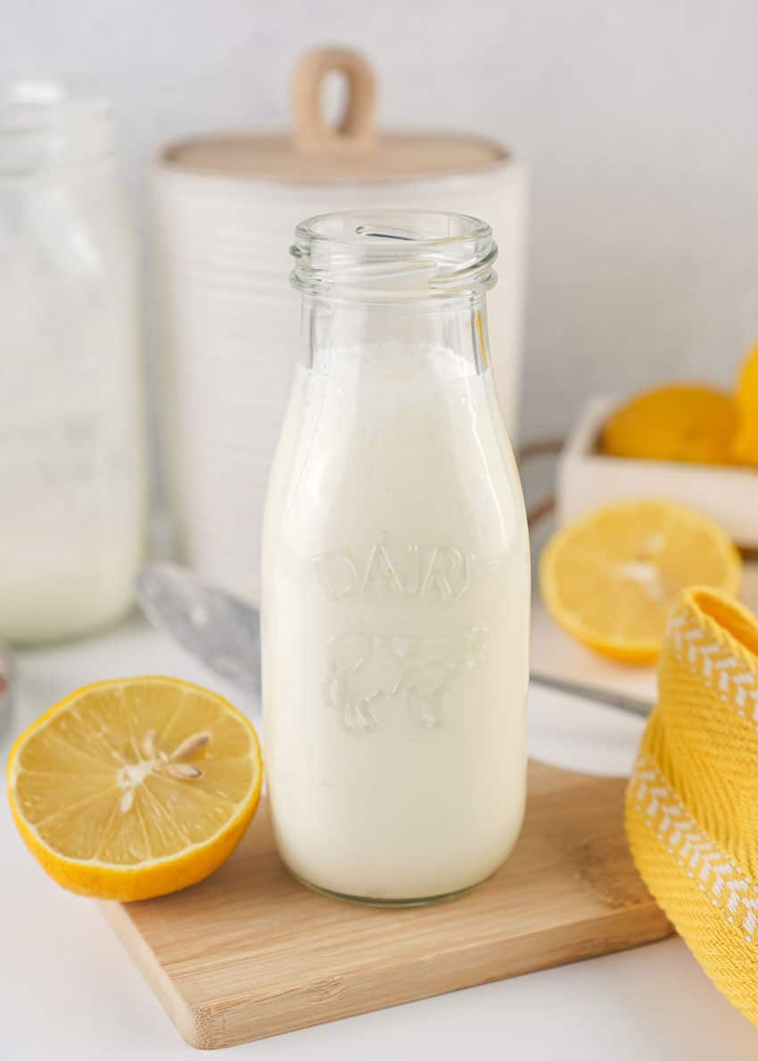 homemade buttermilk in a small glass jar resting on a wooden trivet