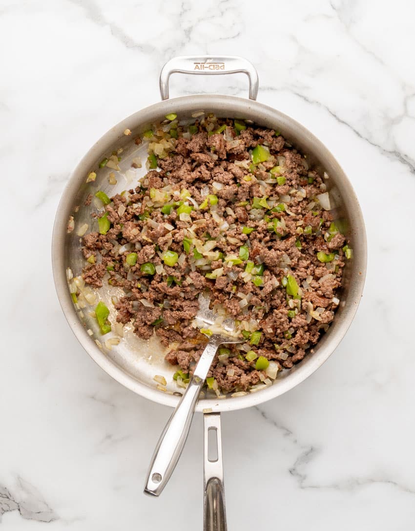 cooked crumbled ground beef with peppers and onions in a large skillet
