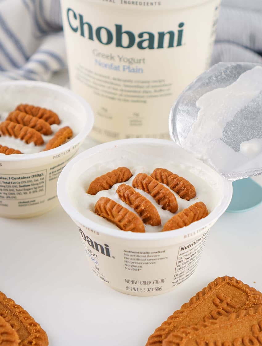 biscoff cookies sitting in two small tubs of plain greek yogurt