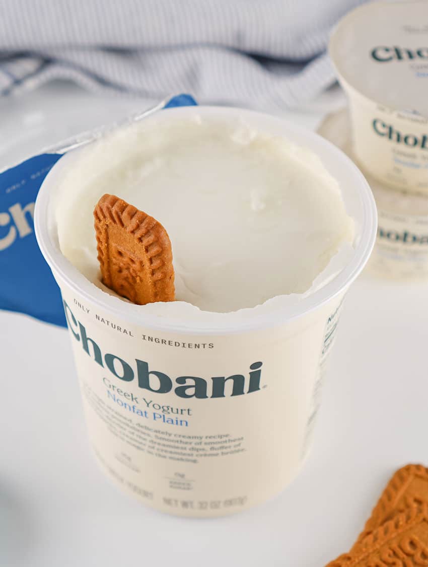 a biscoff cookie sitting in a tub of plain greek yogurt