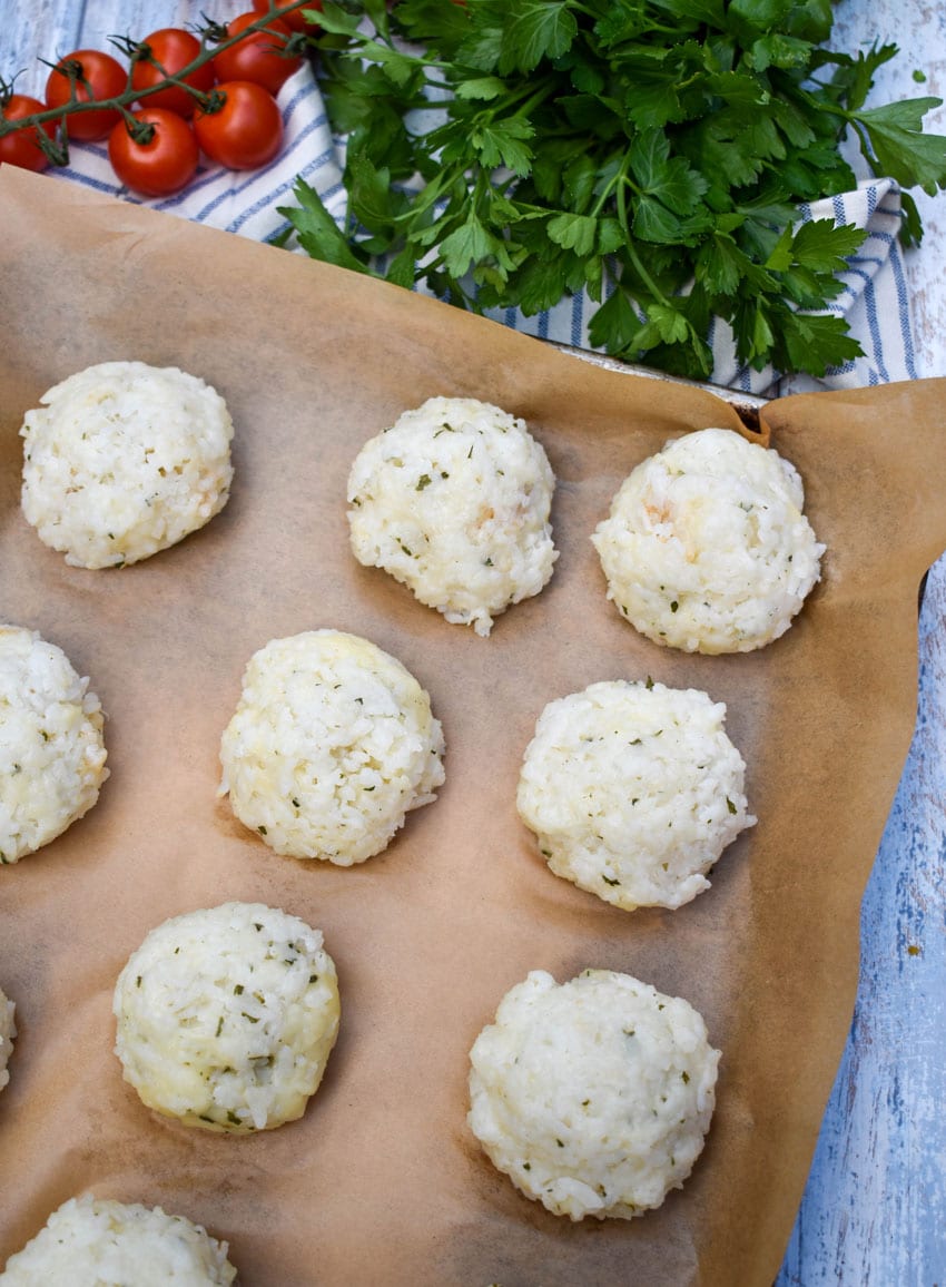frozen rice balls arranged in rows on a parchment paper lined baking sheet