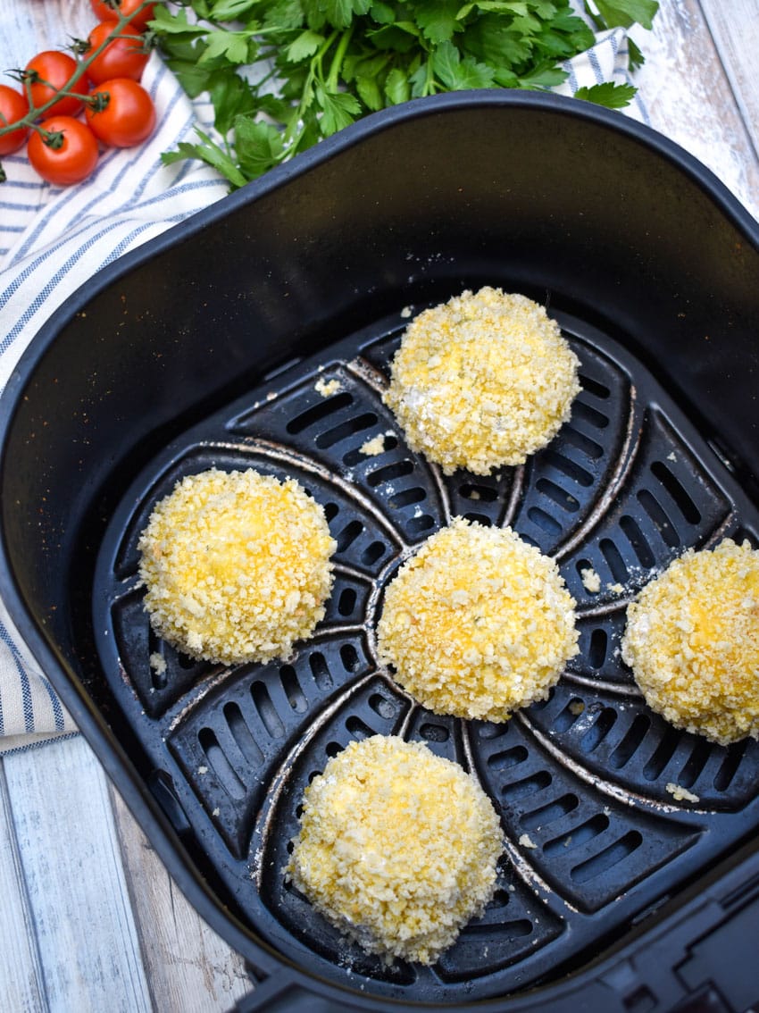 panko bread crumb coated cheesy rice balls in the basket of an air fryer