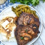 two pieces of copycat Carrabba’s Steak Marsala next to mashed potatoes and green beans on a white plate
