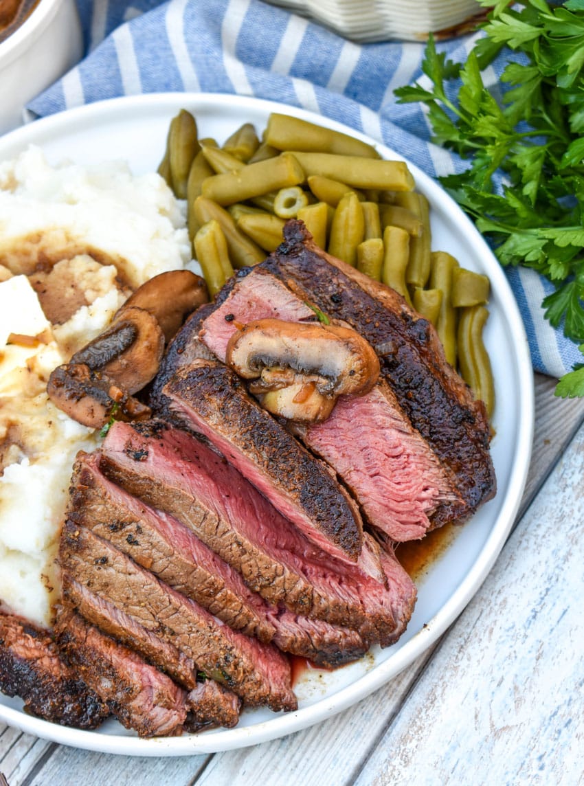 slices of copycat Carrabba’s Steak Marsala next to mashed potatoes and green beans on a white plate