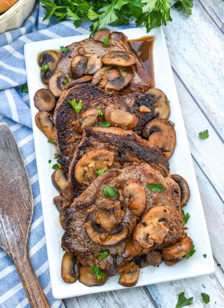 pieces of copycat Carrabba’s Steak Marsala topped with sauteed mushrooms on a white serving platter