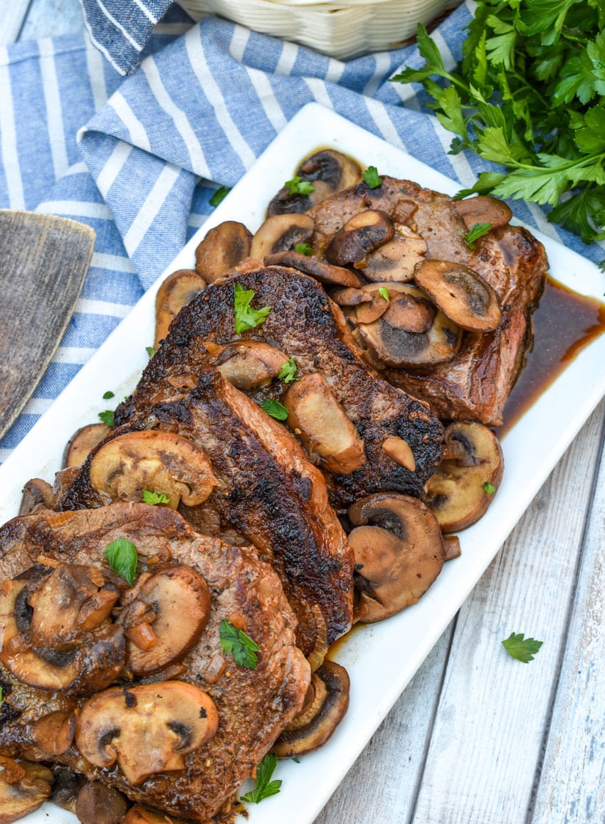 pieces of copycat Carrabba’s Steak Marsala topped with sauteed mushrooms on a white serving platter