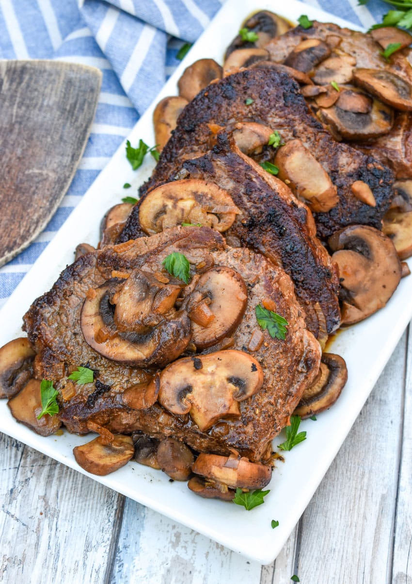pieces of copycat Carrabba’s Steak Marsala topped with sauteed mushrooms on a white serving platter