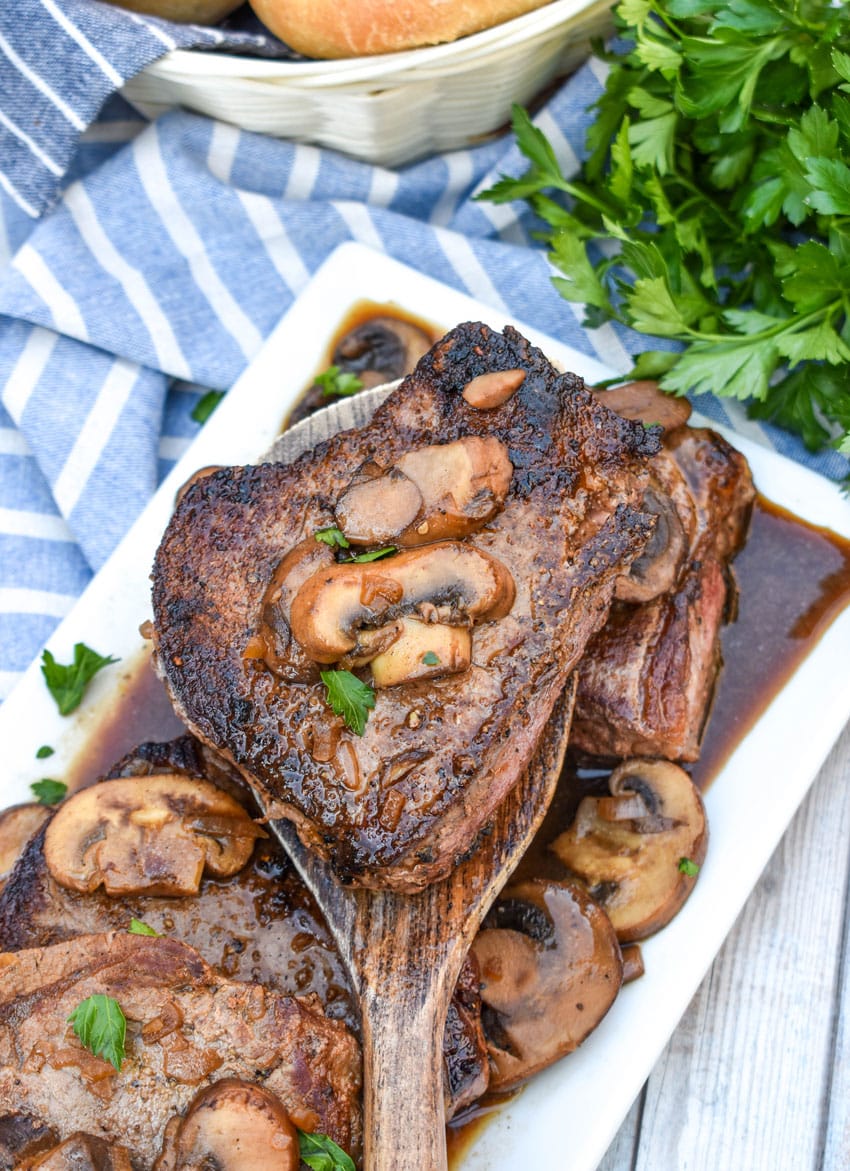 pieces of copycat Carrabba’s Steak Marsala topped with sauteed mushrooms on a white serving platter