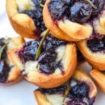 a close up of cranberry brie bites stacked on a white serving plate
