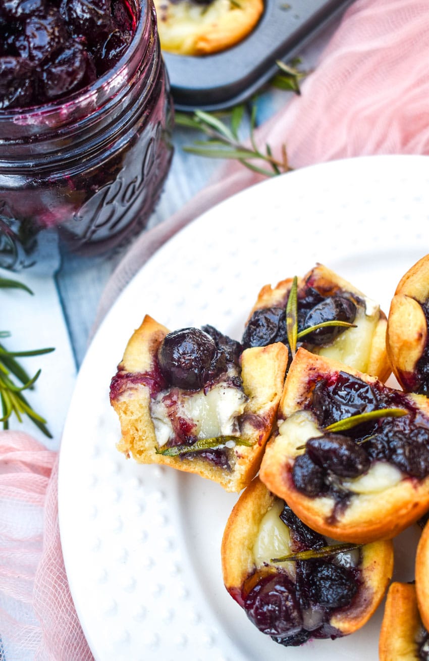 a close up of cranberry brie bites stacked on a white serving plate