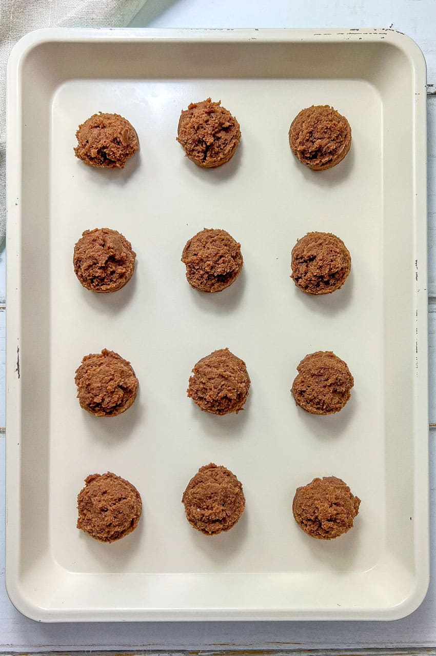 balls of brownie cheesecake dough arranged in three rows on a baking sheet