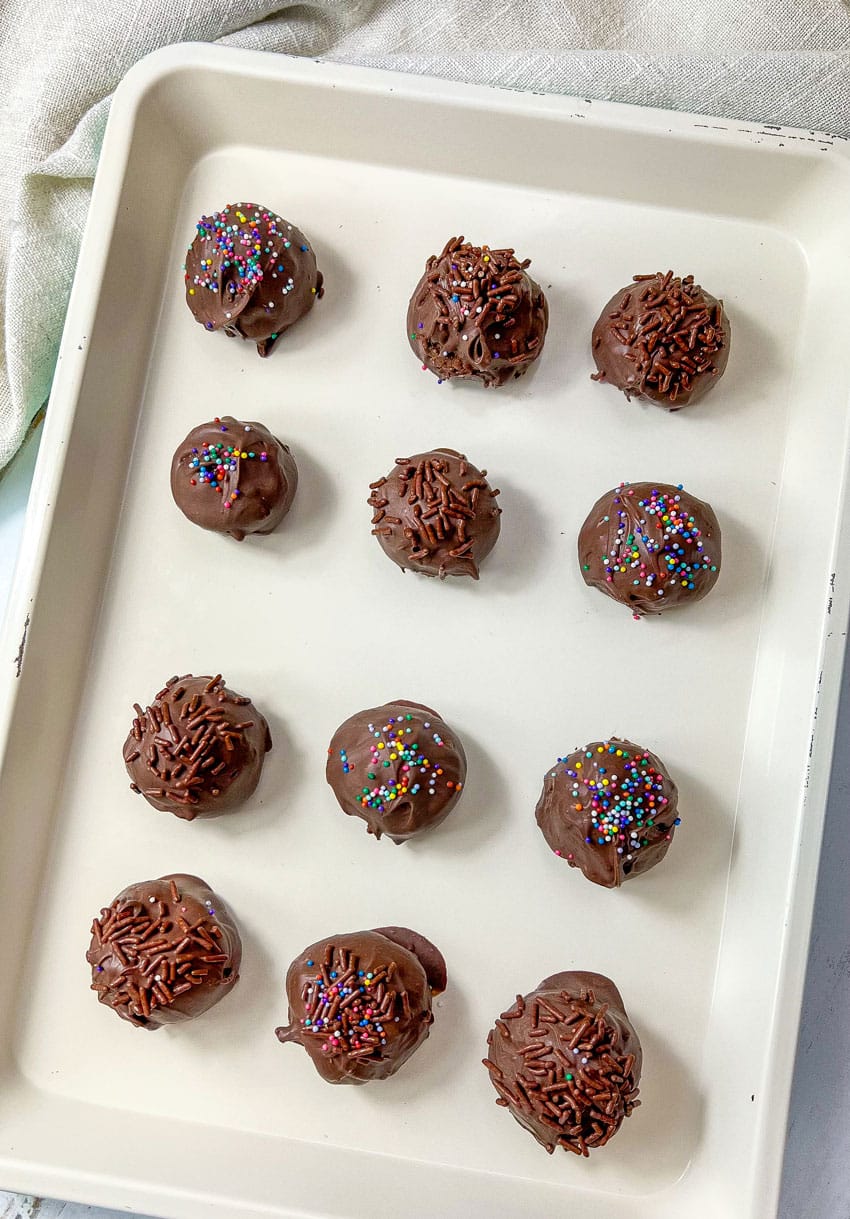 homemade brownie cheesecake truffles arranged in three rows on a baking sheet