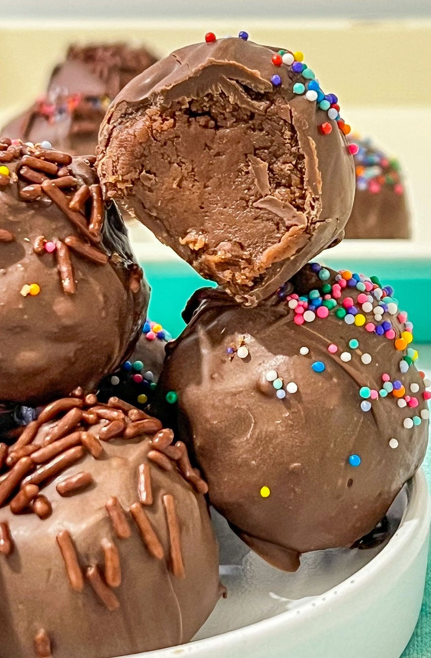 a close up of brownie cheesecake truffles in a small white bowl