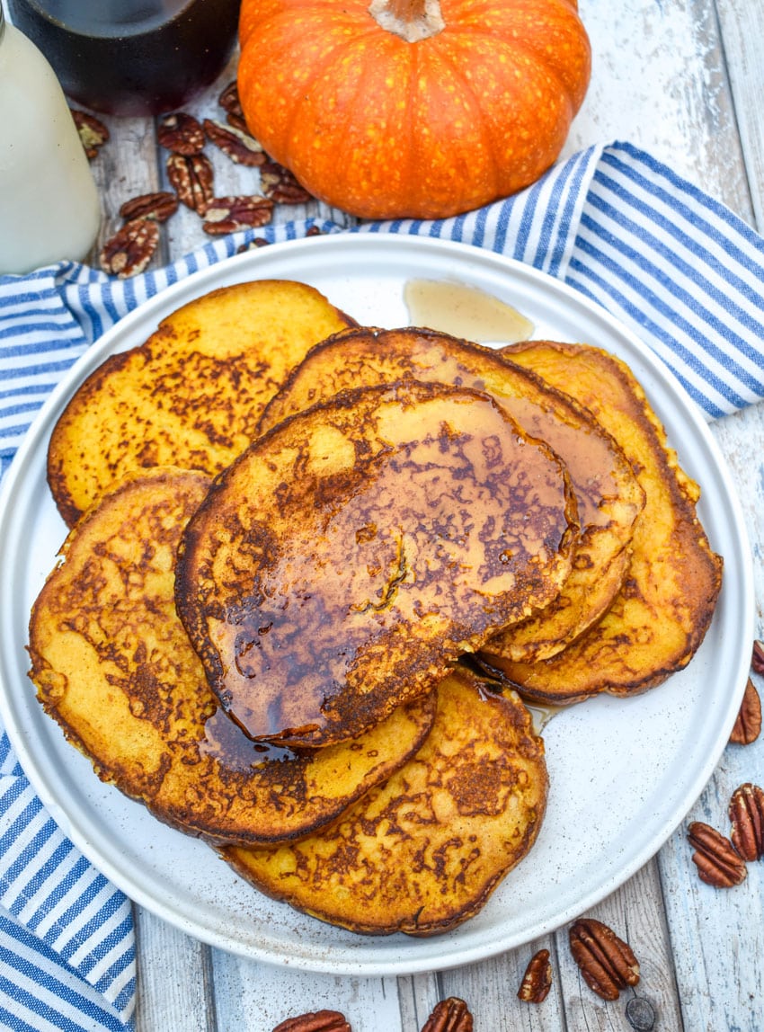 syrup topped slices of pumpkin french toast stacked on a large white plate