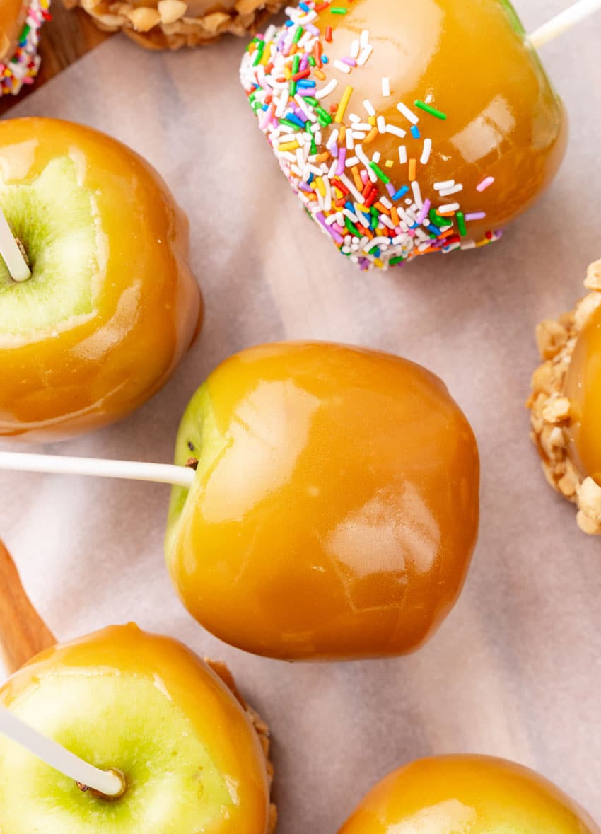 homemade caramel apples on a parchment paper lined baking sheet