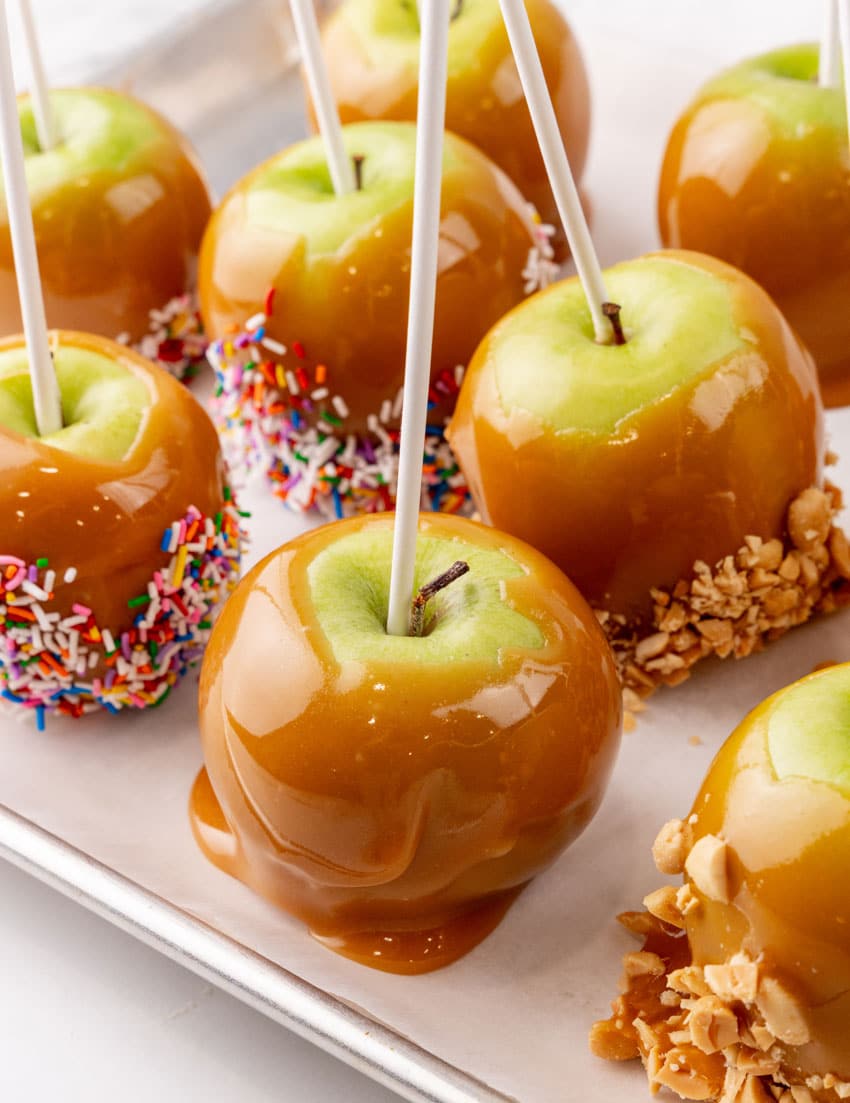 homemade caramel apples on a parchment paper lined baking sheet
