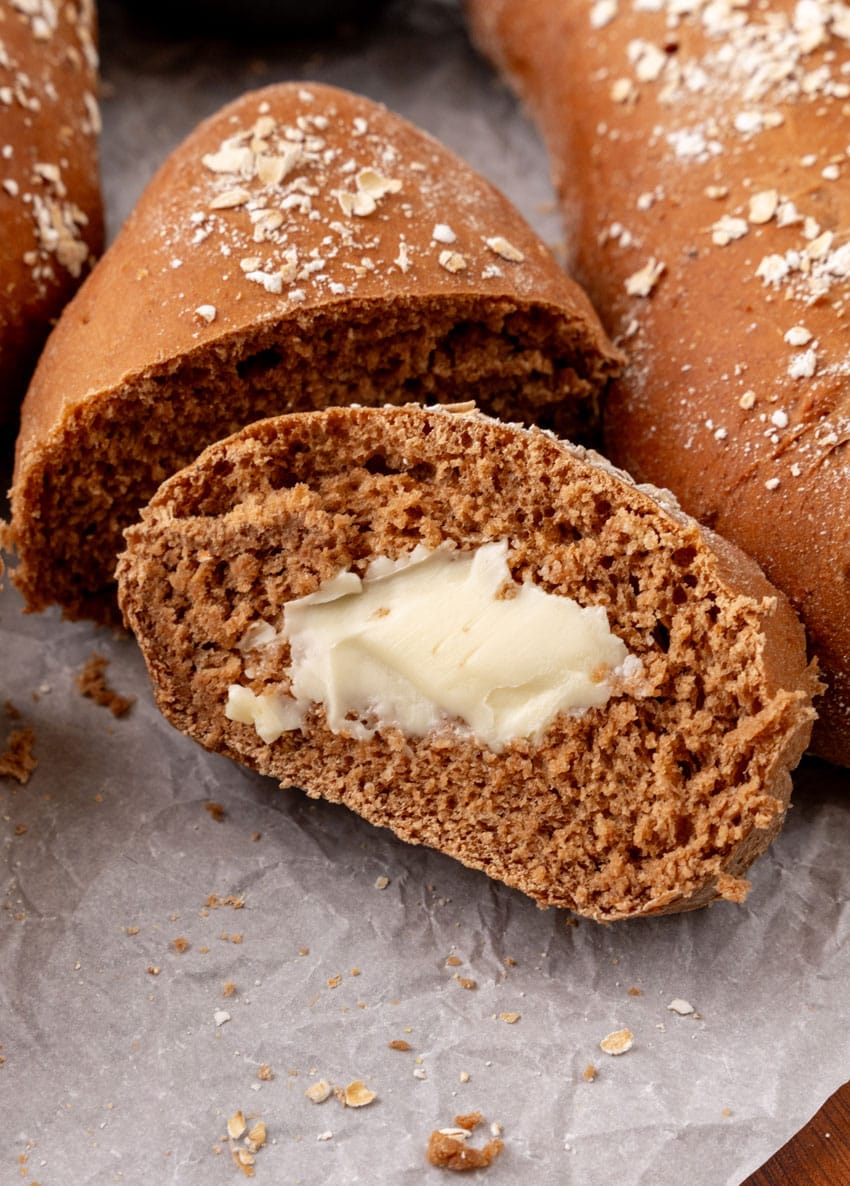 a slice of copycat cheesecake factory brown bread spread with softened butter on a parchment paper lined wooden serving tray
