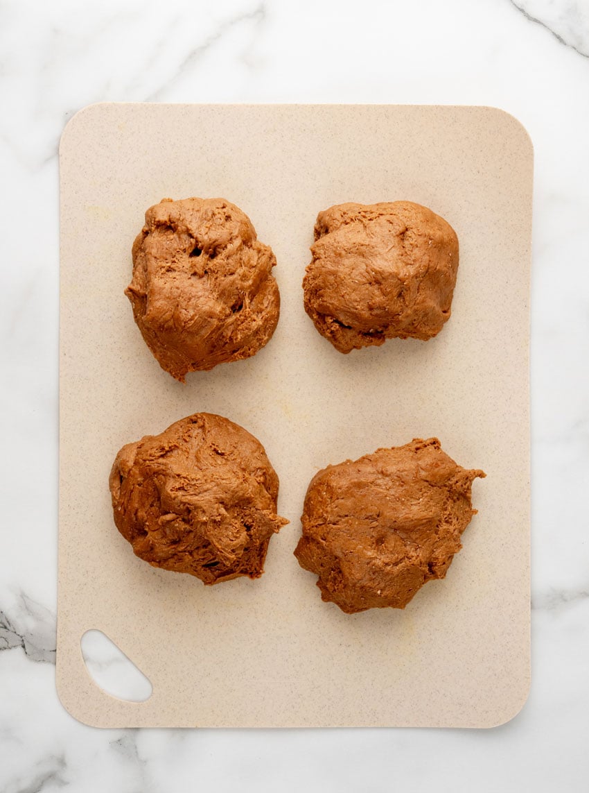 four pieces of homemade cheesecake factory brown bread dough on a plastic cutting board