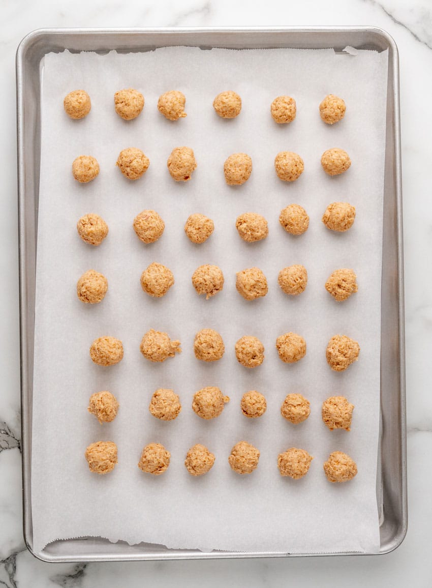 homemade cat treat balls arranged in rows on a parchment paper lined baking tray