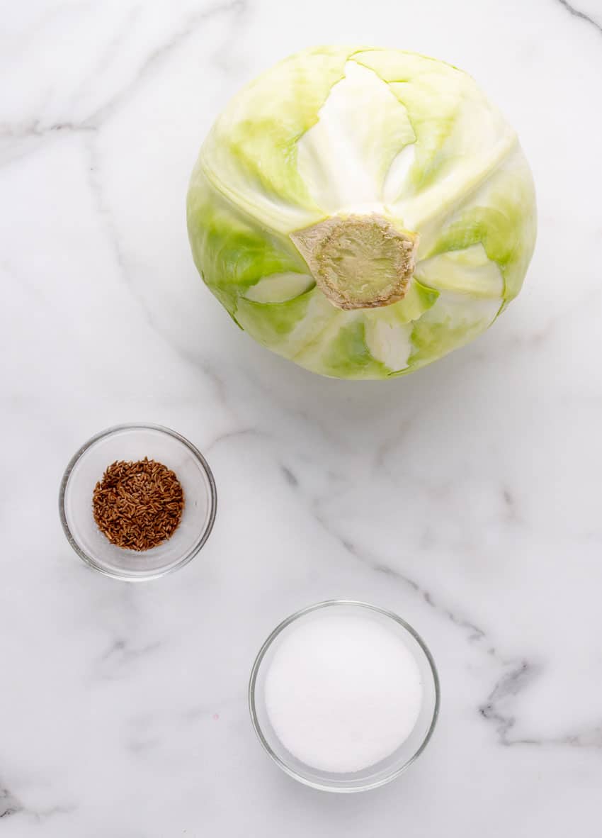 an overhead image showing the measured ingredients needed to make a simple sauerkraut from scratch