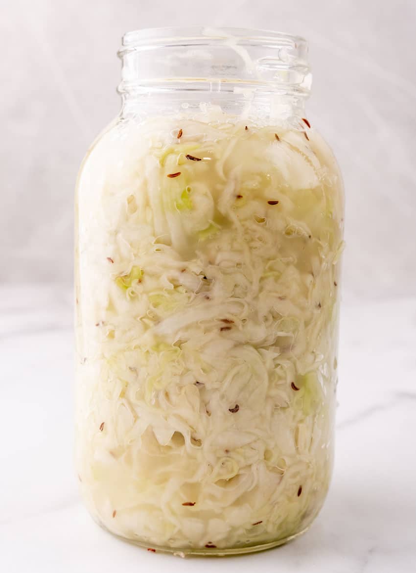 prepared sliced cabbage with brine packed into a large glass jar