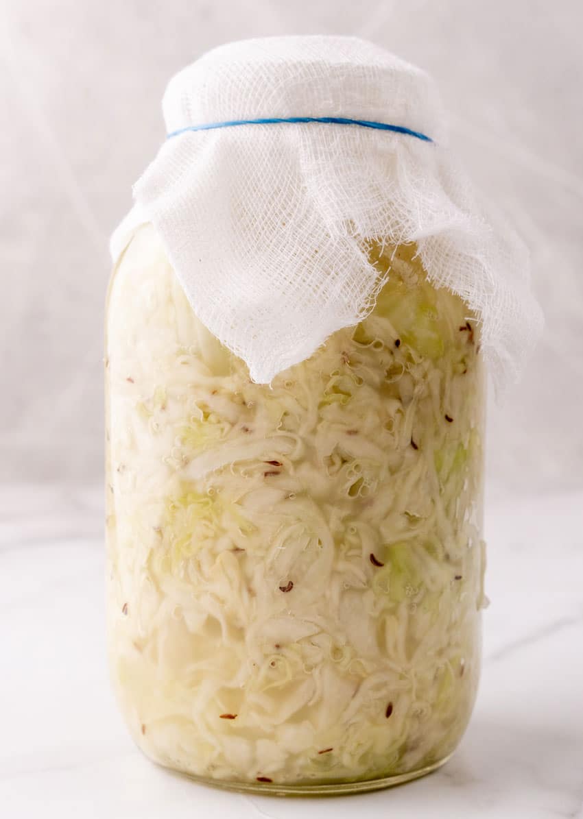 a cheesecloth topped jar of fermenting cabbage