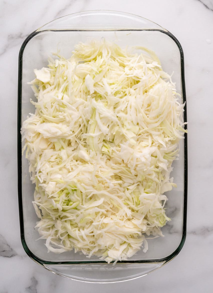 thinly sliced fresh cabbage in a glass baking dish