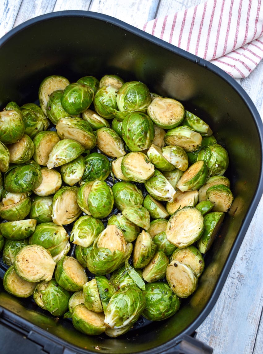olive oil coated halved brussels sprouts in the basket of an air fryer