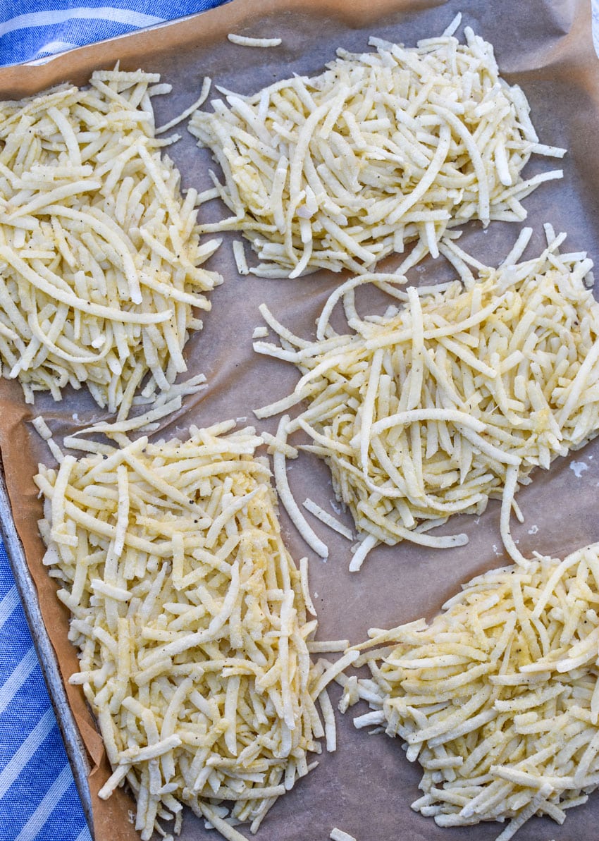 frozen homemade hashbrown patties on a parchment paper lined baking sheet