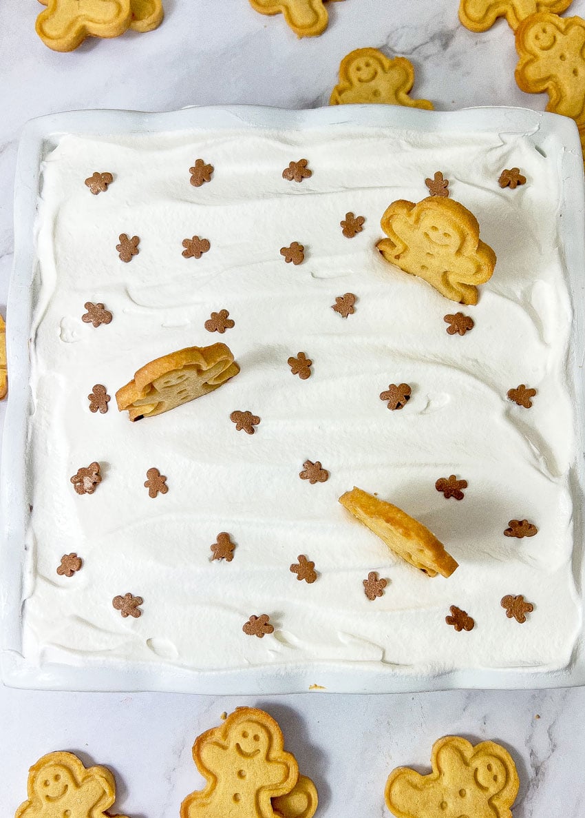 an overhead image showing frosted gingerbread cheesecake bars in a white baking dish